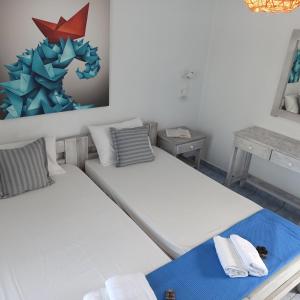 ナウサにあるIsalos Parosのベッド2台が備わる客室で、壁には絵画が飾られています。