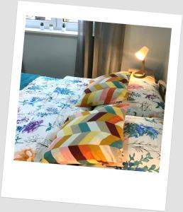 uma cama com um edredão colorido e um candeeiro em Apartament w Alei Fontann. em Szczecin