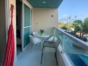 Un balcón con mesa y sillas y una piscina. en Villas do Atlântico APT 208 - Porto de Galinhas, en Porto de Galinhas