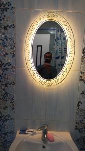 a man taking a picture of a mirror over a sink at Luxury Apartments in Cairo