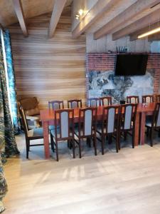 comedor con mesas y sillas de madera y TV en Viesu nams Liepas en Baltais Dukstgals