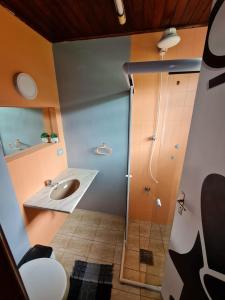 uma casa de banho com um lavatório e um chuveiro em Hostel 4 Elementos - 200 metros da Praia de Pernambuco e do Mar Casado no Guarujá