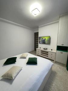 um quarto com uma grande cama branca e uma televisão na parede em Chilia 2 Apartments em Chilia Veche