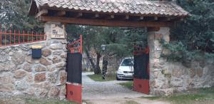 une porte menant à un bâtiment en pierre avec une voiture derrière lui dans l'établissement Exclusiva Casa y Finca Privada ITOS, à Pelayos del Arroyo