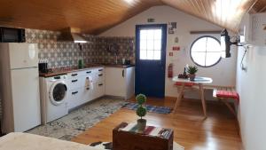 a kitchen with a refrigerator and a table and a door at Casa Villa Dinastía Sótão Y Casa Villa Dinastía Miramar in Ribeira Brava