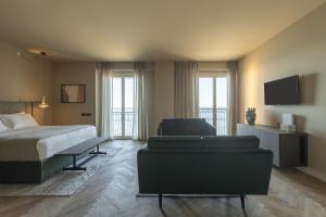 a bedroom with a bed and a couch and a tv at Hotel Windsor in Laigueglia