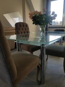 - une table à manger en verre avec un vase de fleurs dans l'établissement Côté Grange, à Tournai