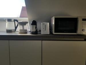 a kitchen counter with a microwave and appliances on it at Côté Grange in Tournai