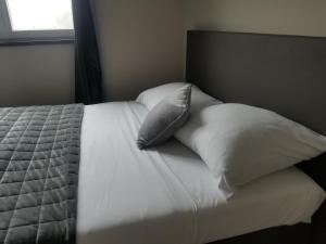 a bed with white sheets and pillows and a window at Côté Grange in Tournai