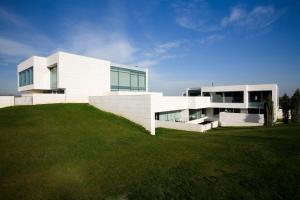 a white building on top of a grass field at Finca Prats Hotel Golf & Spa in Lleida