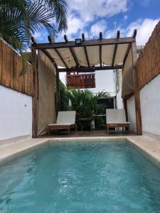 a swimming pool with two chairs and a pergola at Casa Bizu in Bacalar