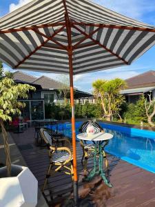 a table and chairs under an umbrella on a deck at Colorful Pool Villa, Chiang Rai, Thailand in Chiang Rai