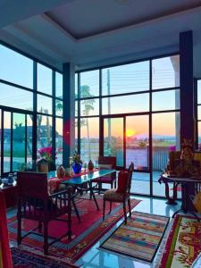 un salon avec une table, des chaises et des fenêtres dans l'établissement Colorful Pool Villa, Chiang Rai, Thailand, à Chiang Rai