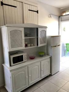 cocina blanca con microondas y nevera en Bel appartement à Damencourt, en Le Moule