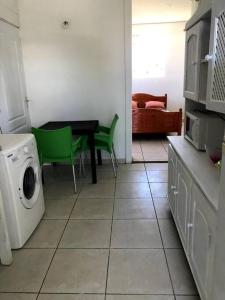 cocina con lavadora y mesa con sillas verdes en Bel appartement à Damencourt, en Le Moule