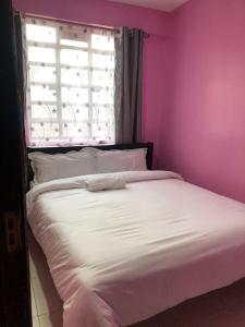 - une chambre rose avec un lit blanc et une fenêtre dans l'établissement Maluhia Halelaa- A9, à Naivasha