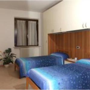 Pokój z 3 niebieskimi łóżkami i lustrem w obiekcie Verde Mare "Appartamenti per Vacanze" w mieście Tortoreto Lido