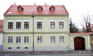 ein großes gelbes Gebäude mit rotem Dach in der Unterkunft 4Rooms Central Sibiu in Sibiu