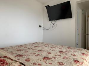 a bedroom with a bed with a tv on the wall at Mirador Villarrica Apartment in Villarrica