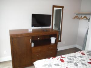 a bedroom with a dresser with a television on it at Motel Beausejour in Neguac