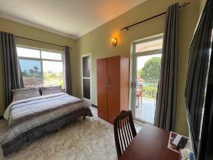 um quarto com uma cama, uma mesa e uma janela em PHYLLEN HOTEL em Tanga