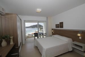 - une chambre avec un lit et une vue sur l'océan dans l'établissement Residencial Jardim dos Beija- Flores, à Bombinhas