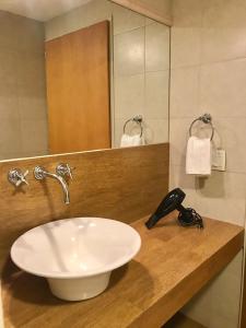 La salle de bains est pourvue d'un lavabo blanc et d'un miroir. dans l'établissement Estudio Vasquitas Bariloche La mejor Ubicación, à San Carlos de Bariloche