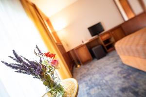 a vase of flowers sitting on a table in a living room at Die Herberge am Lautenberg Bad Loipersdorf in Loipersdorf bei Fürstenfeld