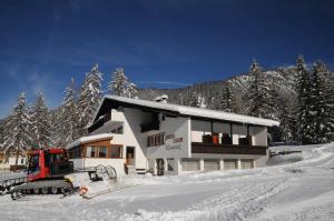 een huis in de sneeuw met een bulldozer ervoor bij Appartments Kameriot in Braies