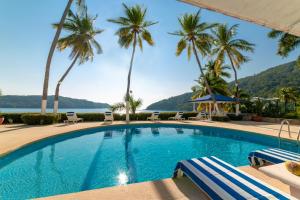 a swimming pool with palm trees and a view of the water at Maravillosa casa con 7 habitaciones, acceso directo a playa pichilingue, bahía de puerto marqués, zona diamante Acapulco in Acapulco