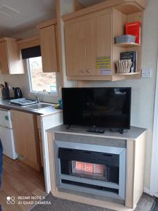 a kitchen with a fireplace with a tv on it at Family Holiday Home - Thorness Bay - WIFI in Porchfield