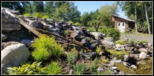 a waterfall in a garden with rocks and plants at La Ruelle Hébergement in Saint-Siméon