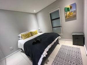 a bedroom with a bed with a black blanket and a window at Seacrest Luxury Beachfront Apartment - Blouberg Beach in Bloubergstrand