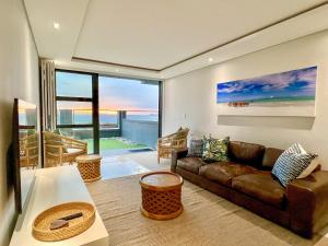 - un salon avec un canapé et une grande fenêtre dans l'établissement Seacrest Luxury Beachfront Apartment - Blouberg Beach, à Bloubergstrand