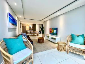 sala de estar con sillas de mimbre y TV en Seacrest Luxury Beachfront Apartment - Blouberg Beach, en Bloubergstrand