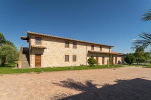 a large stone house with a brick driveway at Lagolivo in Passignano sul Trasimeno