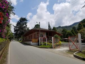 a small building with a fence on the side of a road at Hostal Rio Arabia - Valle De Cocora HOTEL in Salento