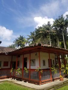 a house with a porch with palm trees in the background at Hostal Rio Arabia - Valle De Cocora HOTEL in Salento