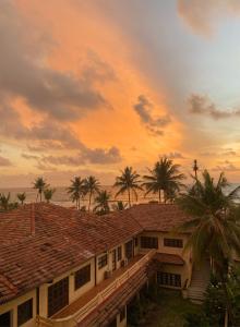 a house with palm trees in front of a sunset at Sea view A in Mount Lavinia