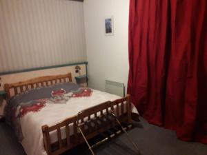 ClellesにあるHotel Restaurant Le Traineauのベッドルーム1室(ベッド1台、赤いカーテン付)