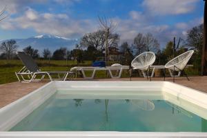 a swimming pool with two chairs and a table and a table and a mountain at Iris 3 in Paralia Katerinis