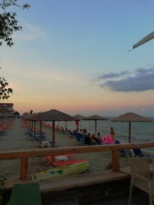 a beach with people sitting on chairs and umbrellas at Iris 3 in Paralia Katerinis