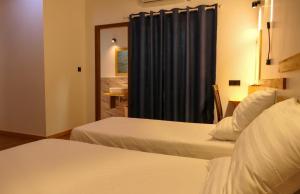 Habitación de hotel con 2 camas y cortina azul en AYIRA Maldives, en Feridhoo