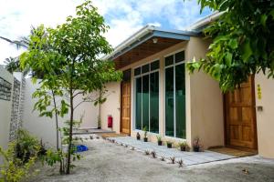een huis met een deur en bomen ervoor bij AYIRA Maldives in Feridhoo