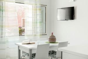 a white dining room with a white table and a tv at Nuovo trilocale vicino centro/mare in Santa Teresa Gallura