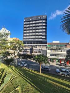 a tall building with a palm tree in front of it at Hotel Europa in Blumenau