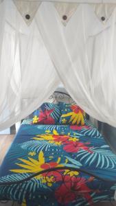 a bed with a colorful comforter on top of it at Les Bougainvilliers Tropicaux in Sans Pareil
