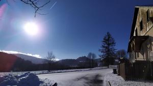 a snow covered road next to a house with the sun in the sky at Haus Tolštejn in Jiřetín pod Jedlovou