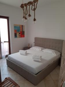 a bedroom with a bed with white sheets and a chandelier at Casa BiBa in Villasimius +31 photos