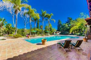 a swimming pool with two chairs and palm trees at Vineyard Hacienda in El Cajon